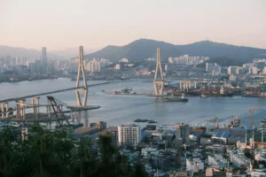 Busan harbour at dusk, the view across the large suspension bridge includes the various high-rise blocks and the sea freight port