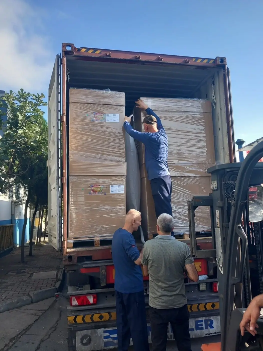 Workers load shipping container with boxes on pallets 