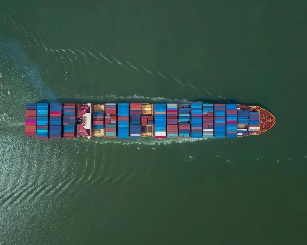 Sea Freight Vessel with Shipping Containers sailing - arial view
